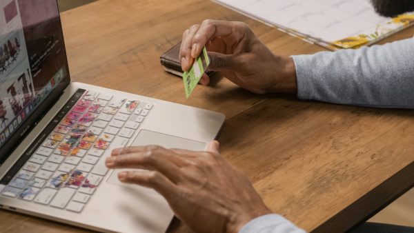 a person using a laptop holding a credit card